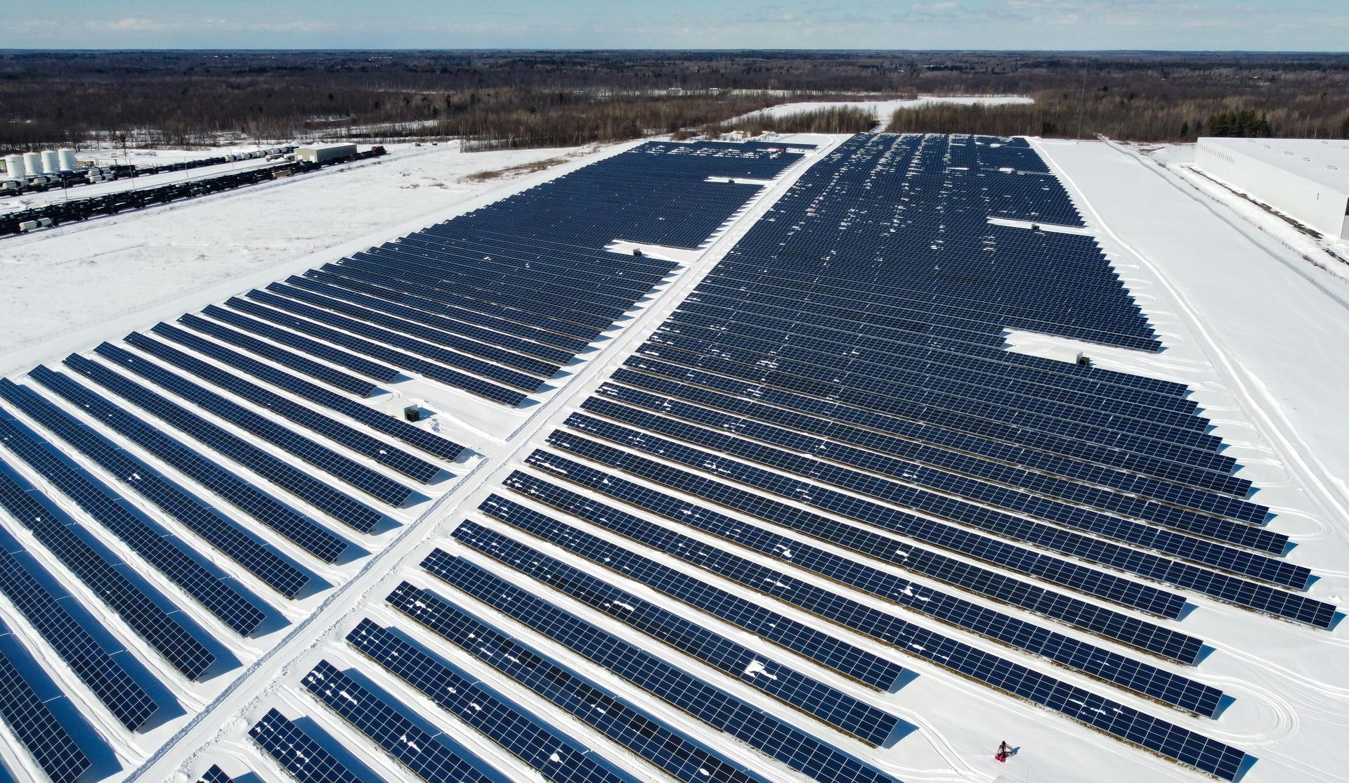 Rows of solar panels in a snowy field under a clear sky