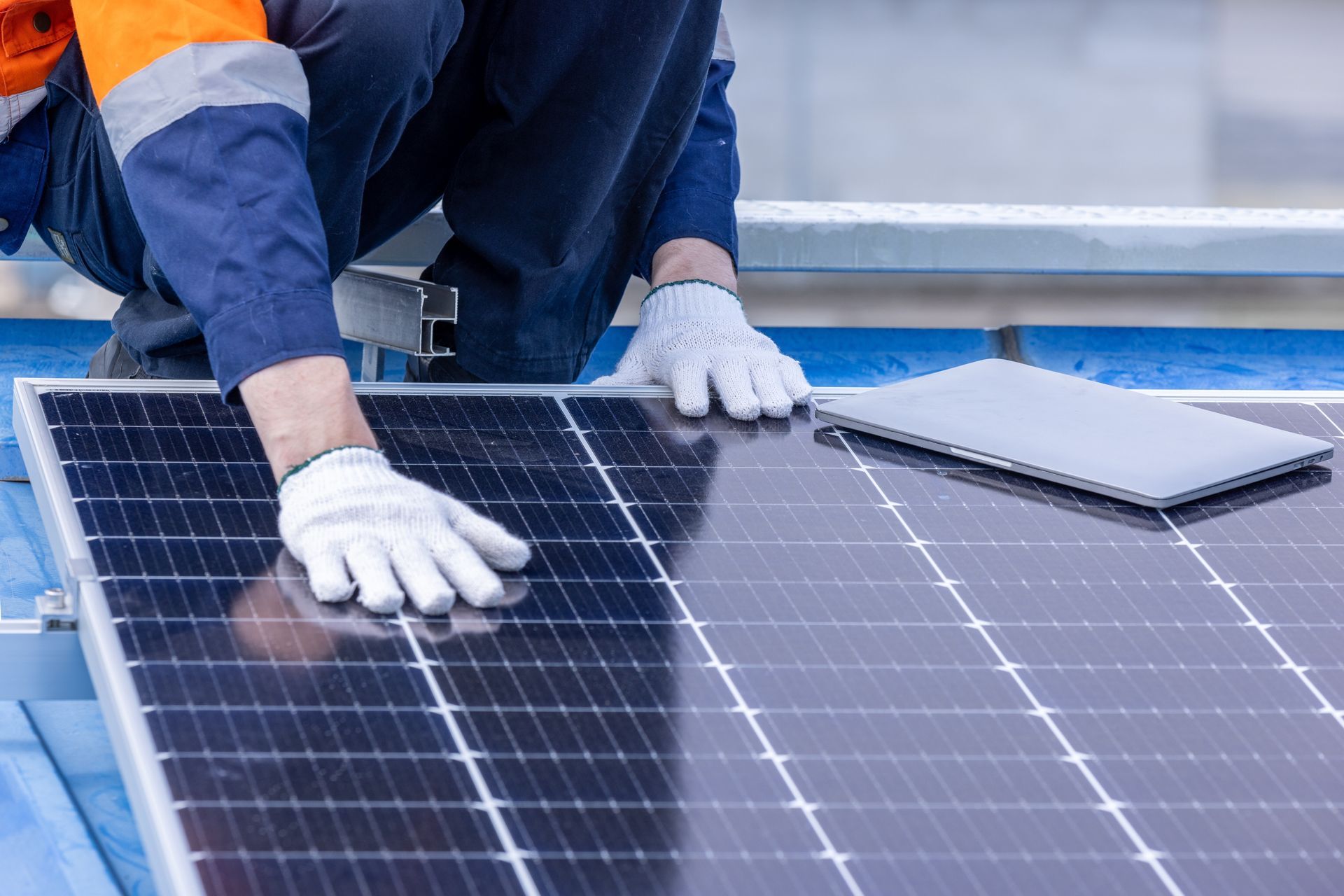 Person in work clothes installing solar panel on a roof.