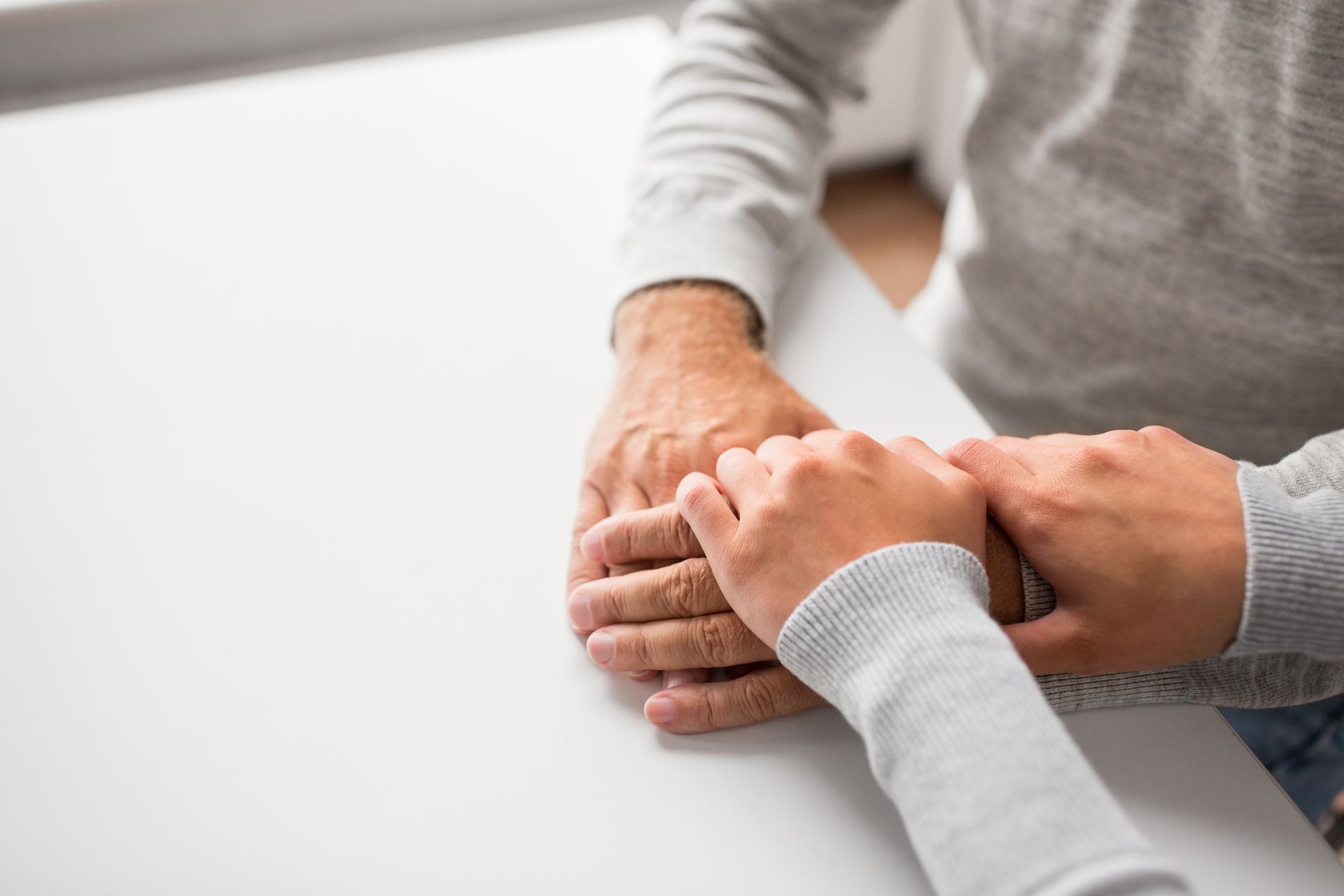 A woman is holding a man 's hand while sitting at a table.