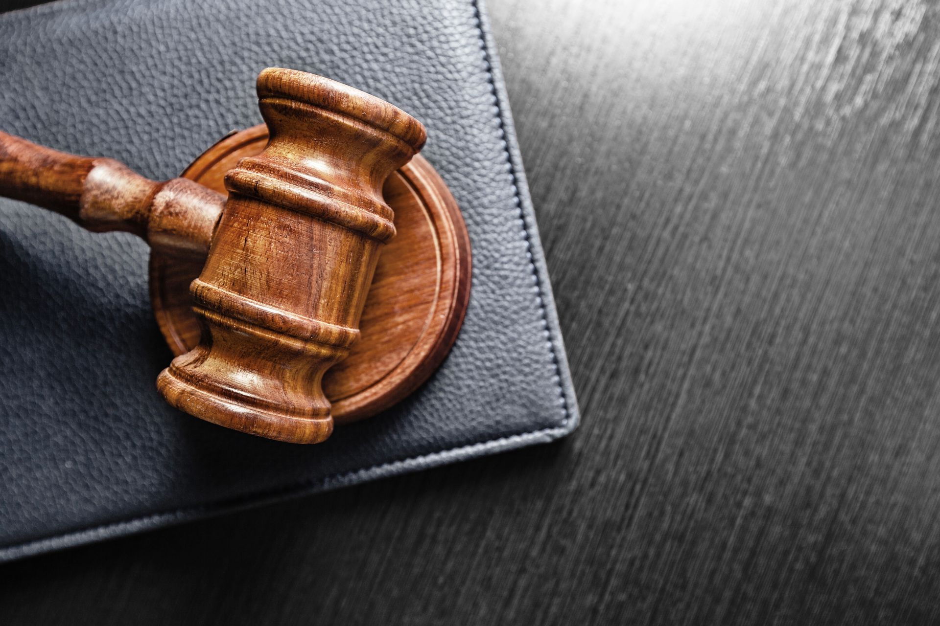 A wooden judge 's gavel is sitting on top of a leather wallet.