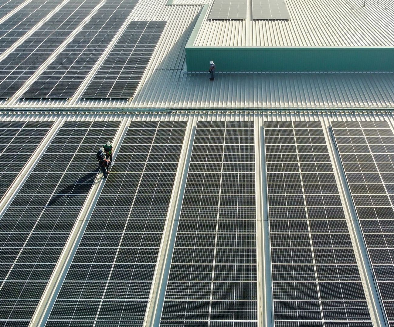 two men are working on the roof of a building with solar panels