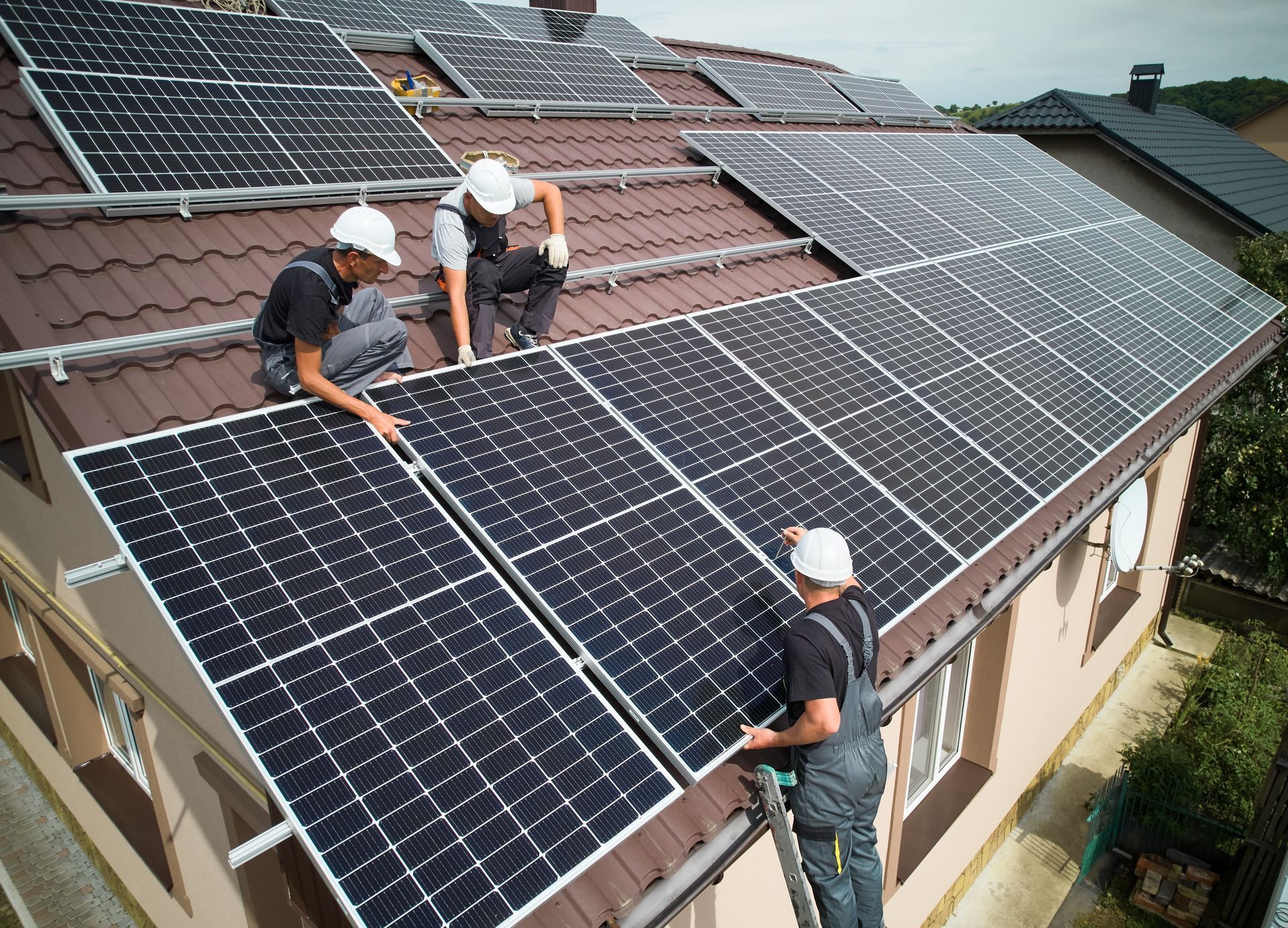 three men are installing solar panels on the roof of a house