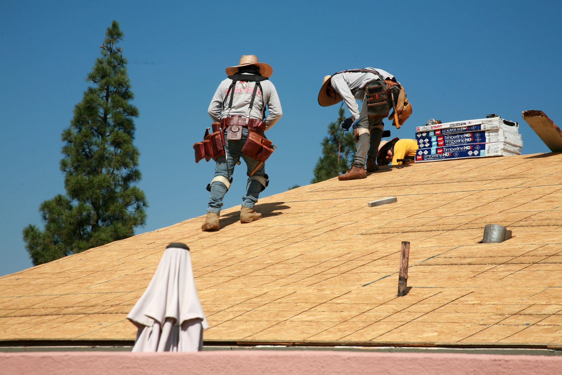 two men are working on a roof with a stack of styrofoam in the background