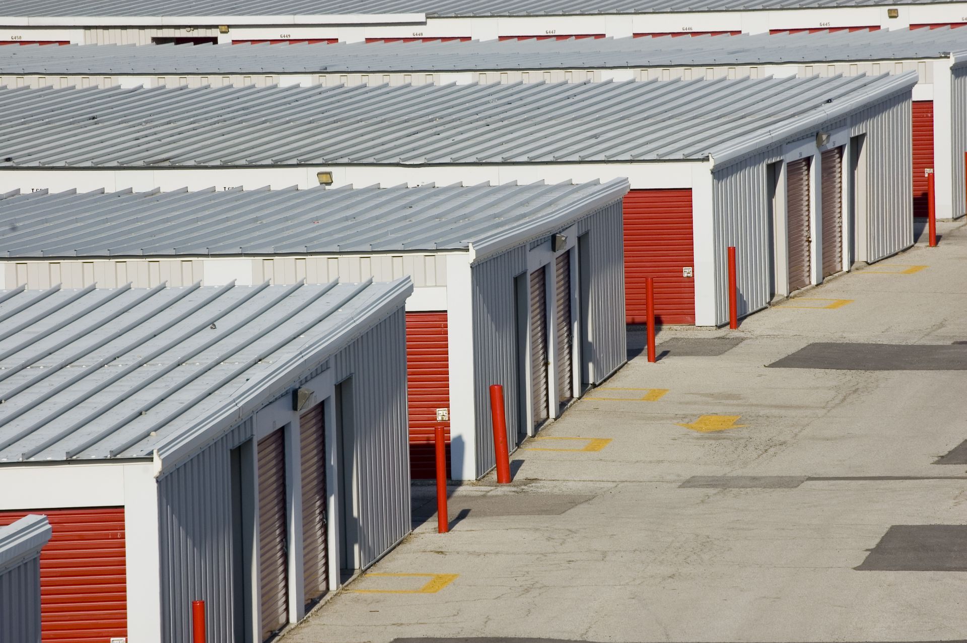 a row of storage units with red doors and a silver roof