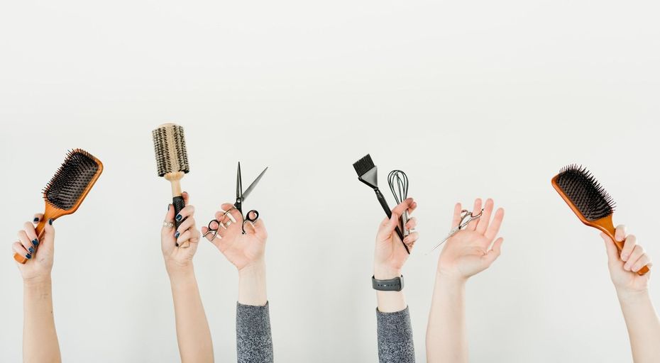 A group of people are holding up their hair brushes and scissors.
