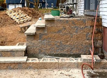 A brick wall is being built in front of a house.