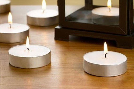 Candles are lit on a wooden table next to a lantern