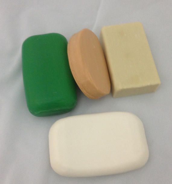 Four different colored soap bars are sitting on a white surface