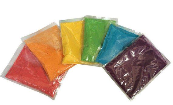 A bunch of bags of different colored powder on a white background.