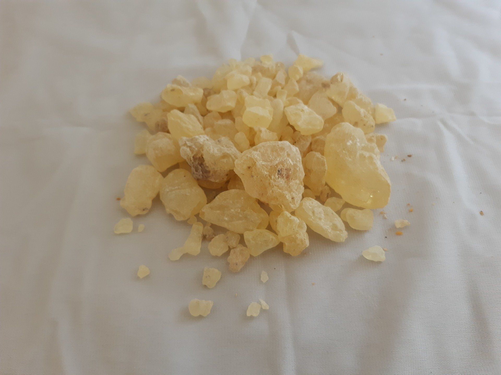 A pile of yellow stones is sitting on a white cloth.
