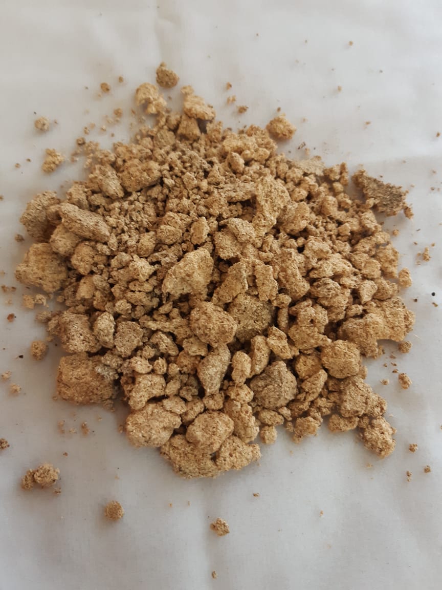 A pile of brown powder is sitting on a white surface.