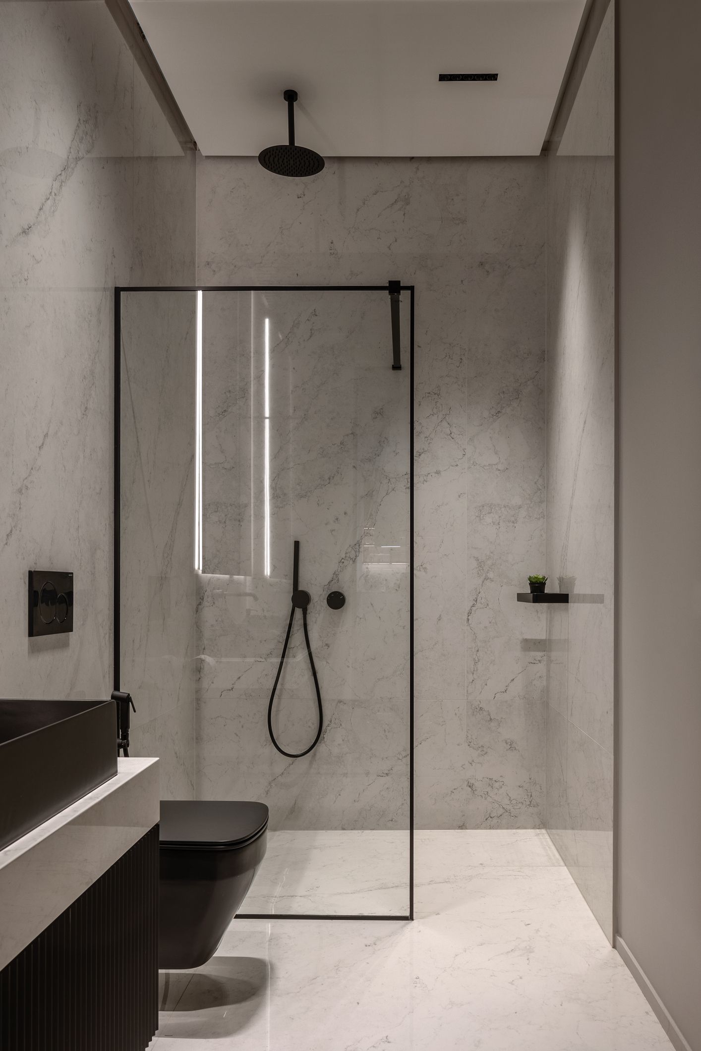 Modern bathroom with black fixtures, marble walls, and a glass shower enclosure.