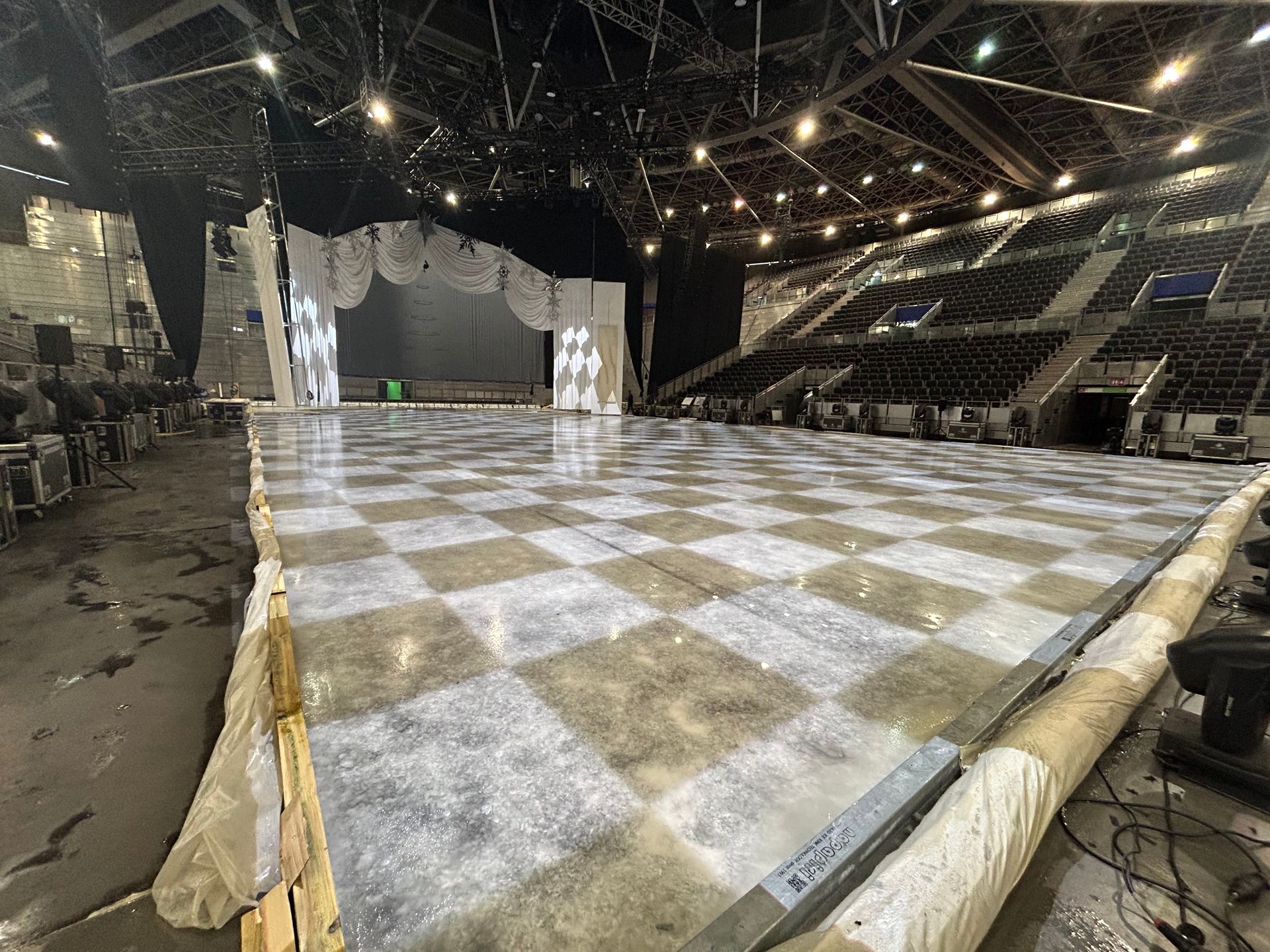 Un gran estadio vacío con suelo cuadriculado y un escenario.