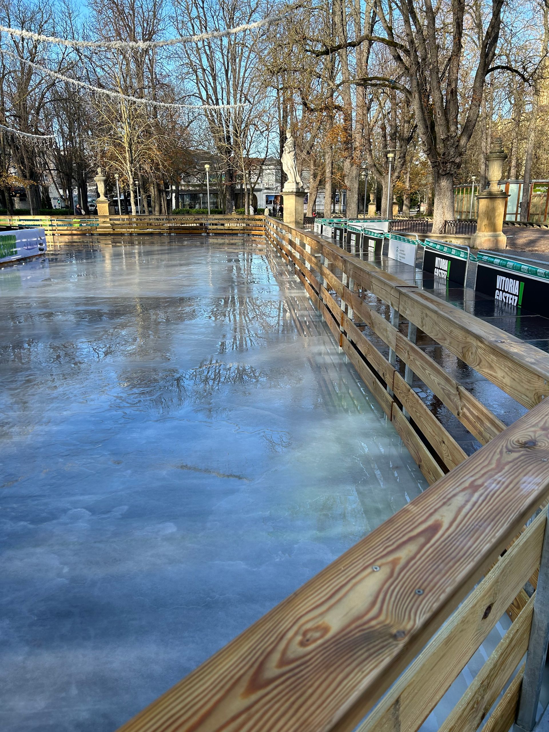 Un puente de madera sobre un lago congelado con árboles al fondo.
