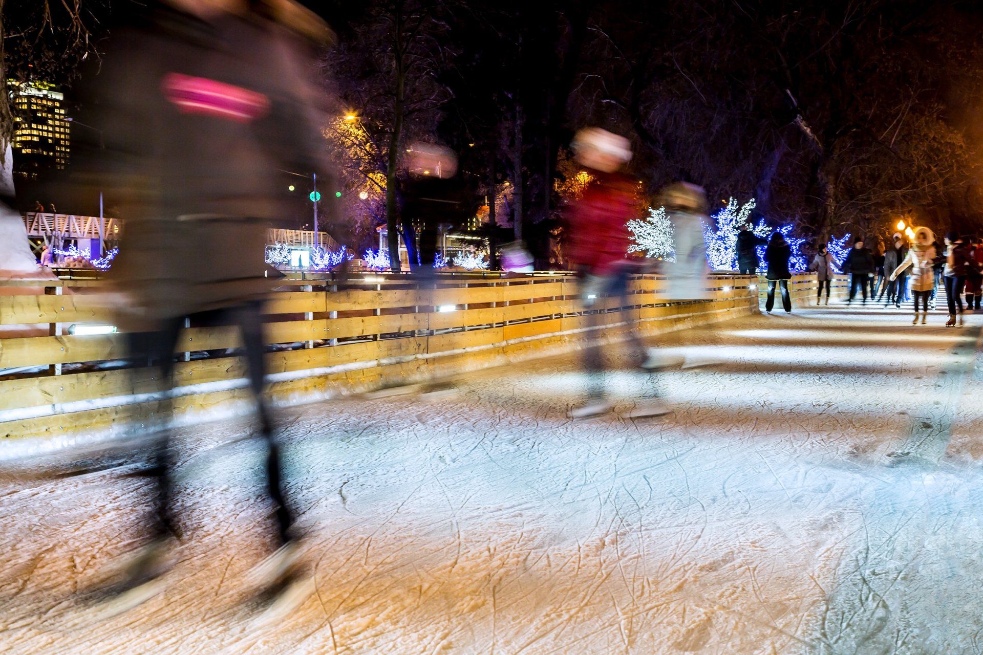 Una imagen borrosa de personas patinando sobre hielo en una pista por la noche.