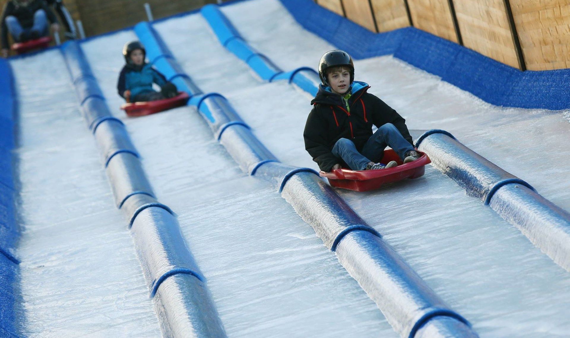 Niños bajando en trineo de un tobogán sobre hielo