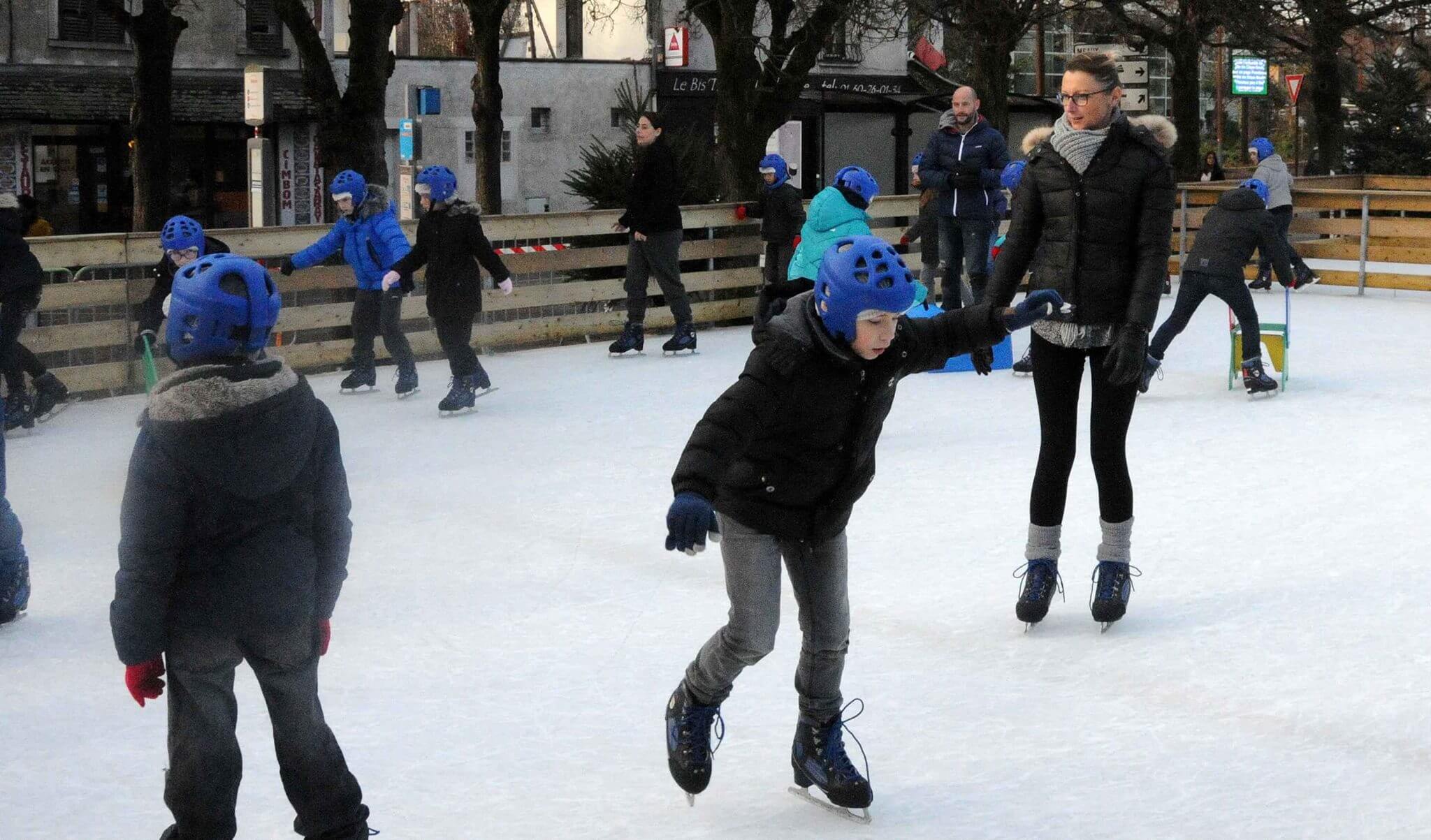 Familia patinando sobre hielo en una pista de hielo móvil al aire libre