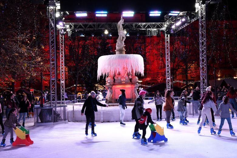 Personas patinando alrededor de una fuente congelada en una pista de hielo