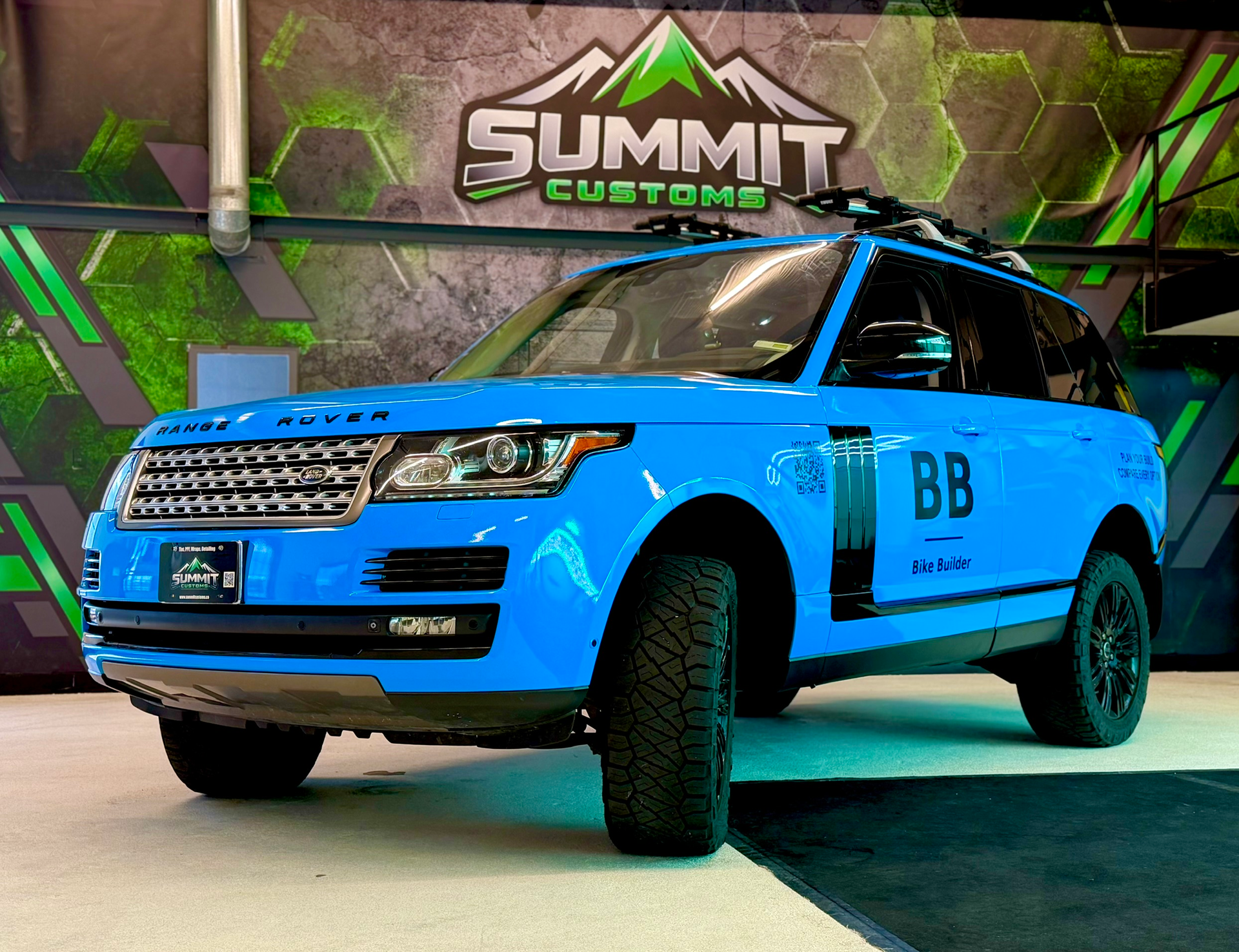 Black SUV parked indoors under green neon lights in a car showroom