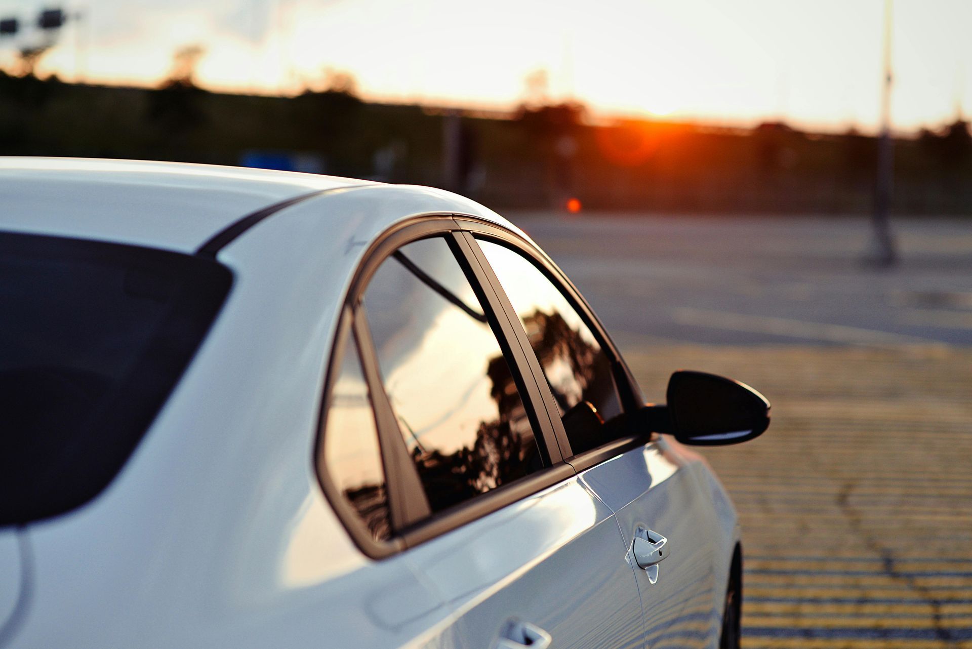 A close-up of a dark car hood with a partially applied, slightly cloudy paint protection film showing swirl patterns.