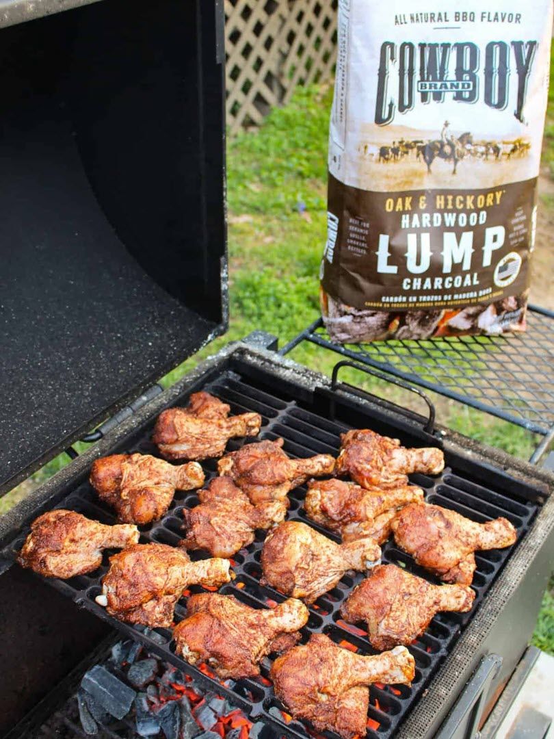 chicken drumsticks on grill with bag of Cowboy Oak & Hickory Lump in background