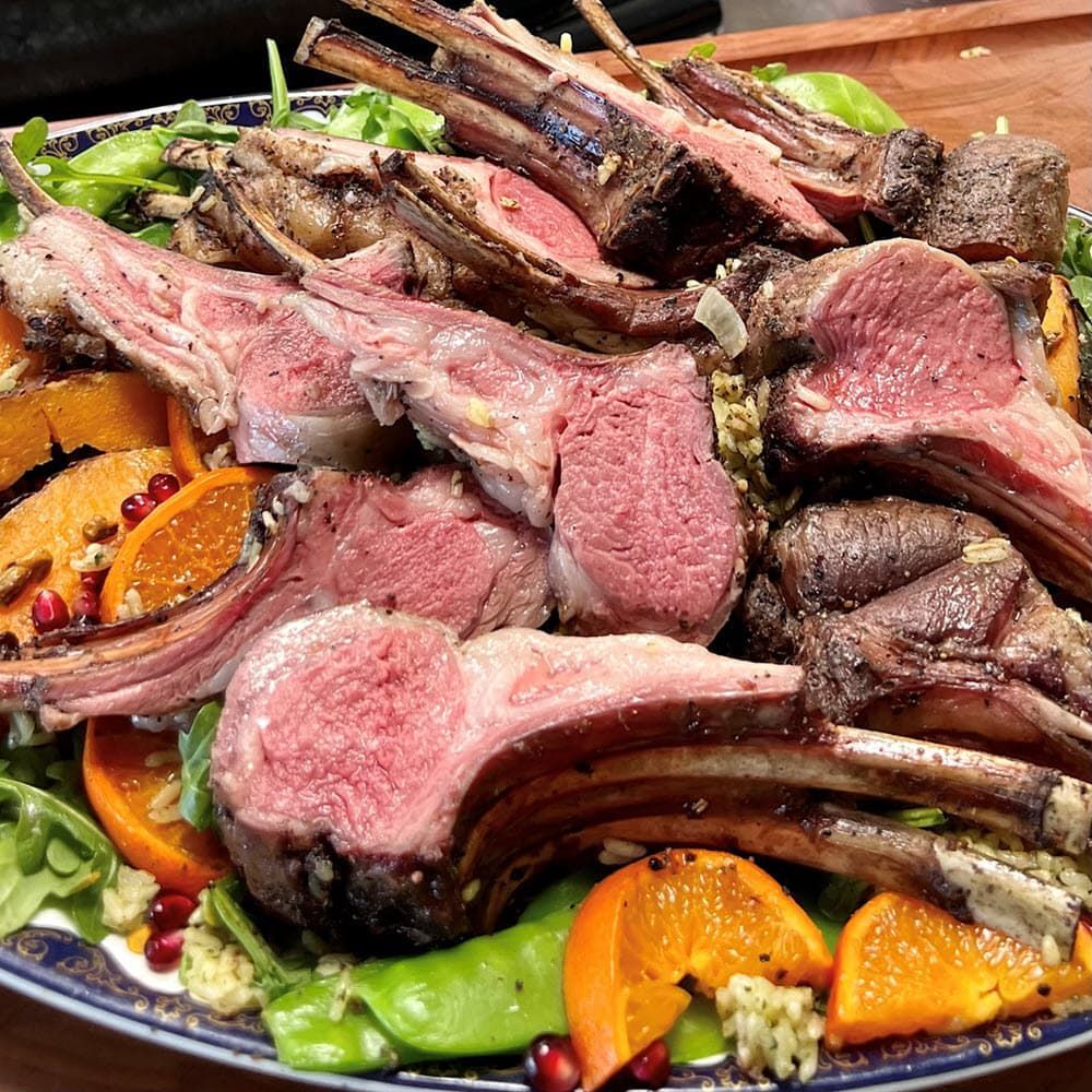 a plate of lamb chops and vegetables on a platter
