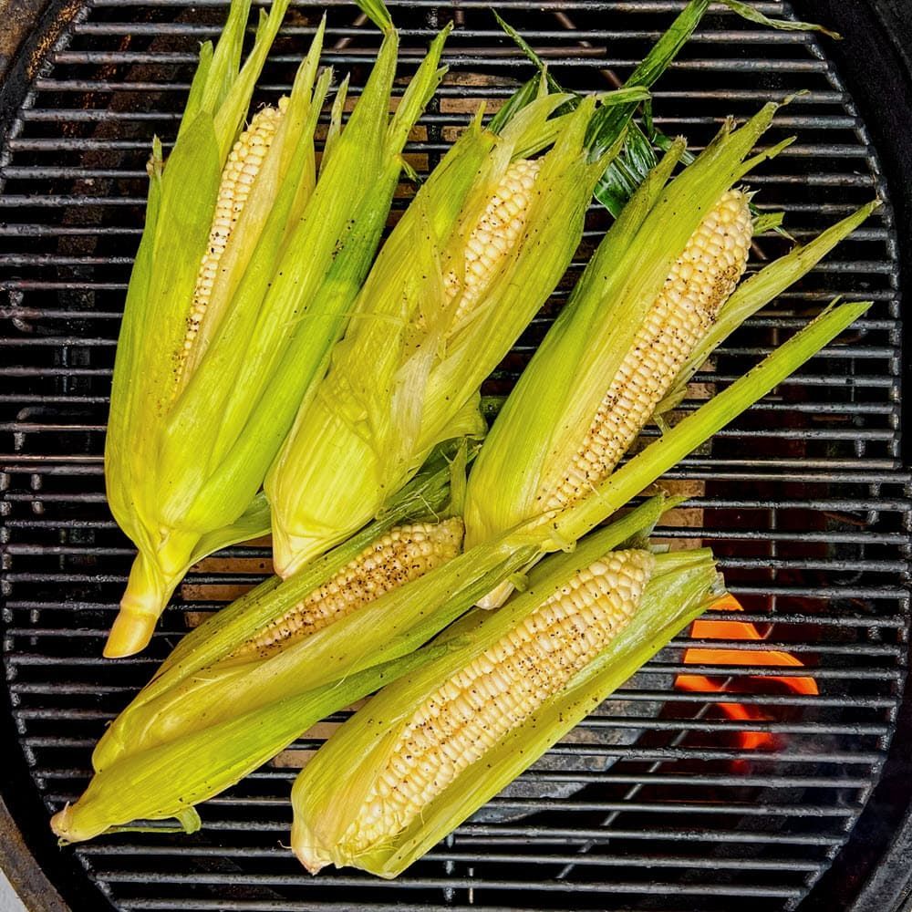 Birdseye view of Corn in husks over live fire on grill