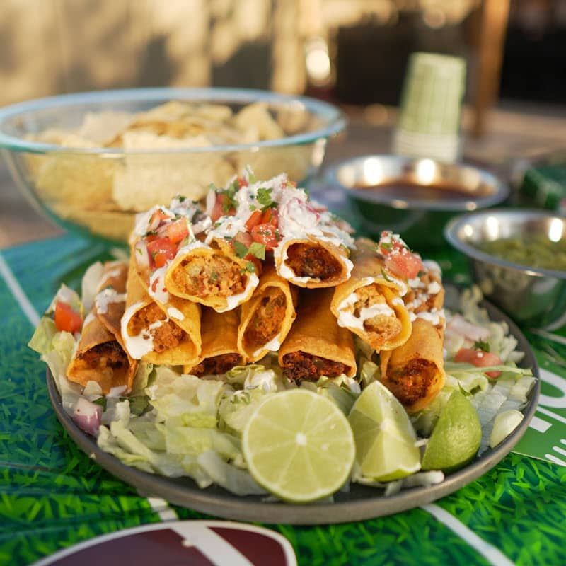 Chicken taquitos topped with cheese and salsa on a bed of lettuce