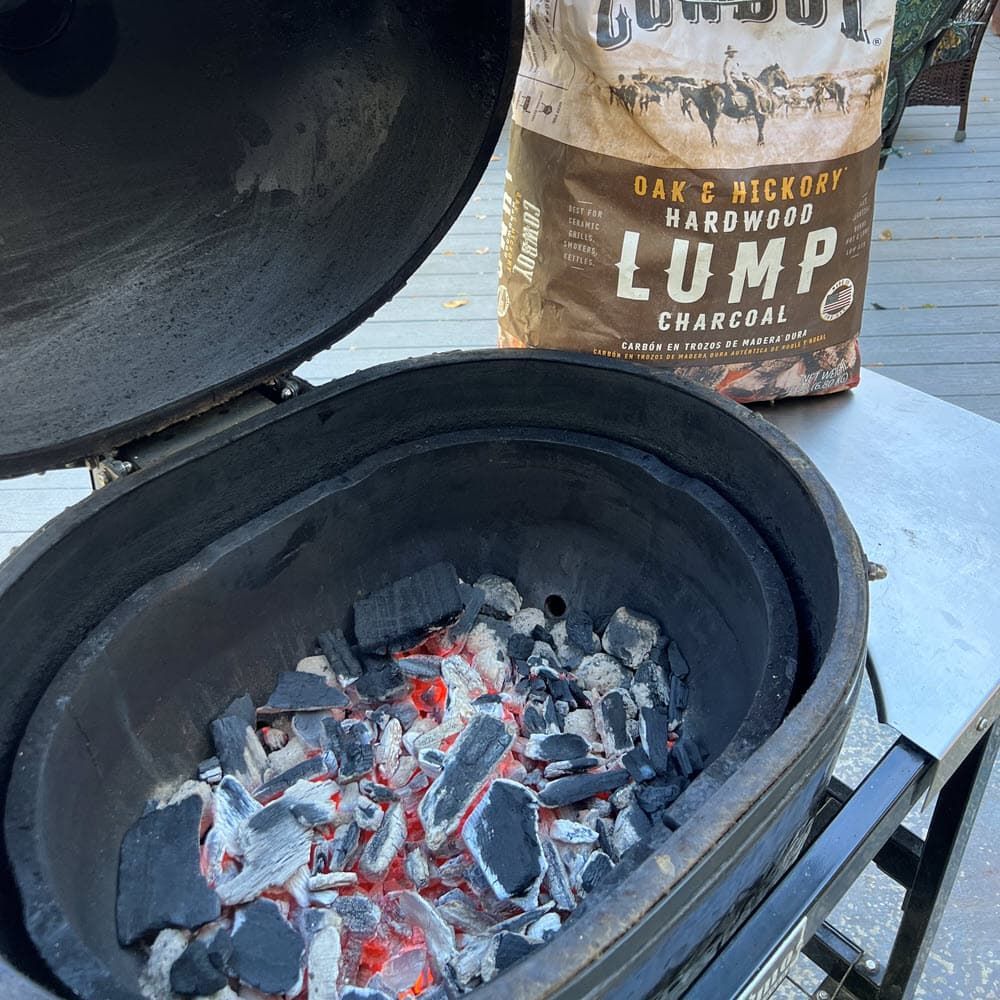 a bag of lump charcoal is sitting next to a grill filled with ashed over lump