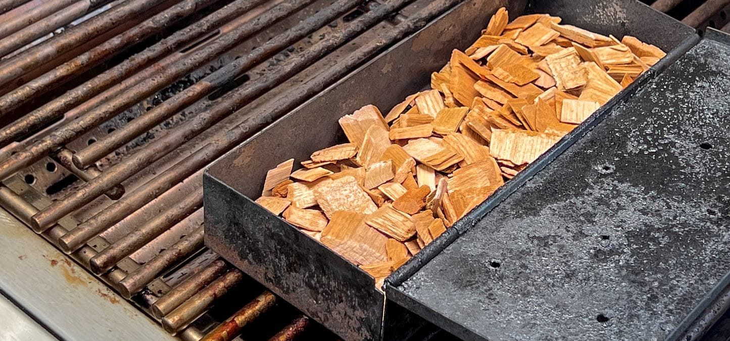 A box of wood chips is sitting on top of a grill.