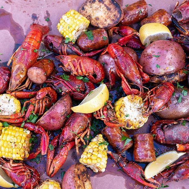 Cajun-style seafood boil with crawfish, corn, potatoes, and lemon wedges piled together