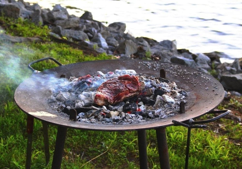 Steak cooking directly over live fire coals in a firepit