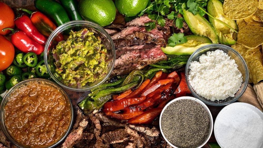 Peppers, salsas, avocado, steak, onions, pepper, limes, tortilla chips, cheese, crema for a fully loaded fajita bar