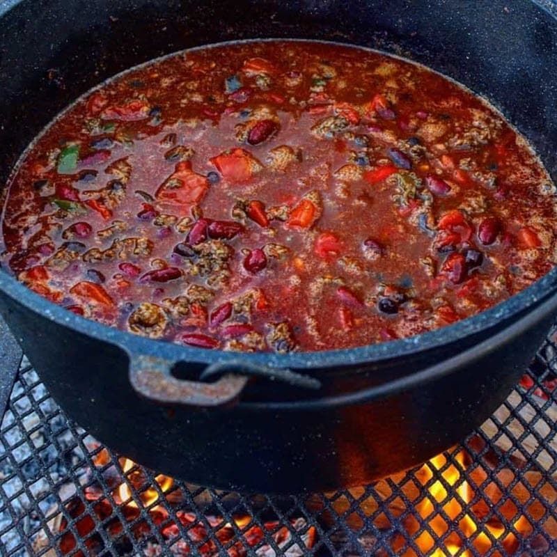 fall festive chili cooking over live fire in cast iron pan