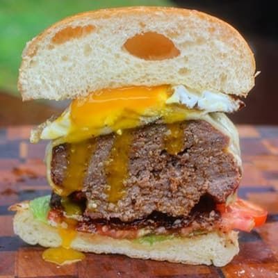 cross-section of burger with lettuce, tomato, beef, cheese and a fried egg