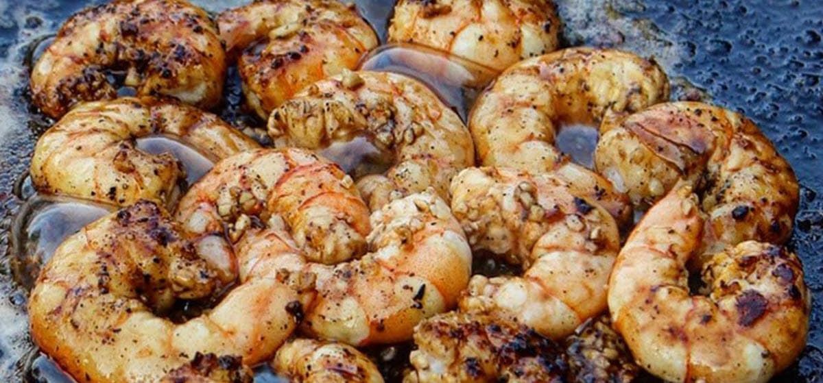 Charred shrimp cooking in  garlic butter in a cast iron pan
