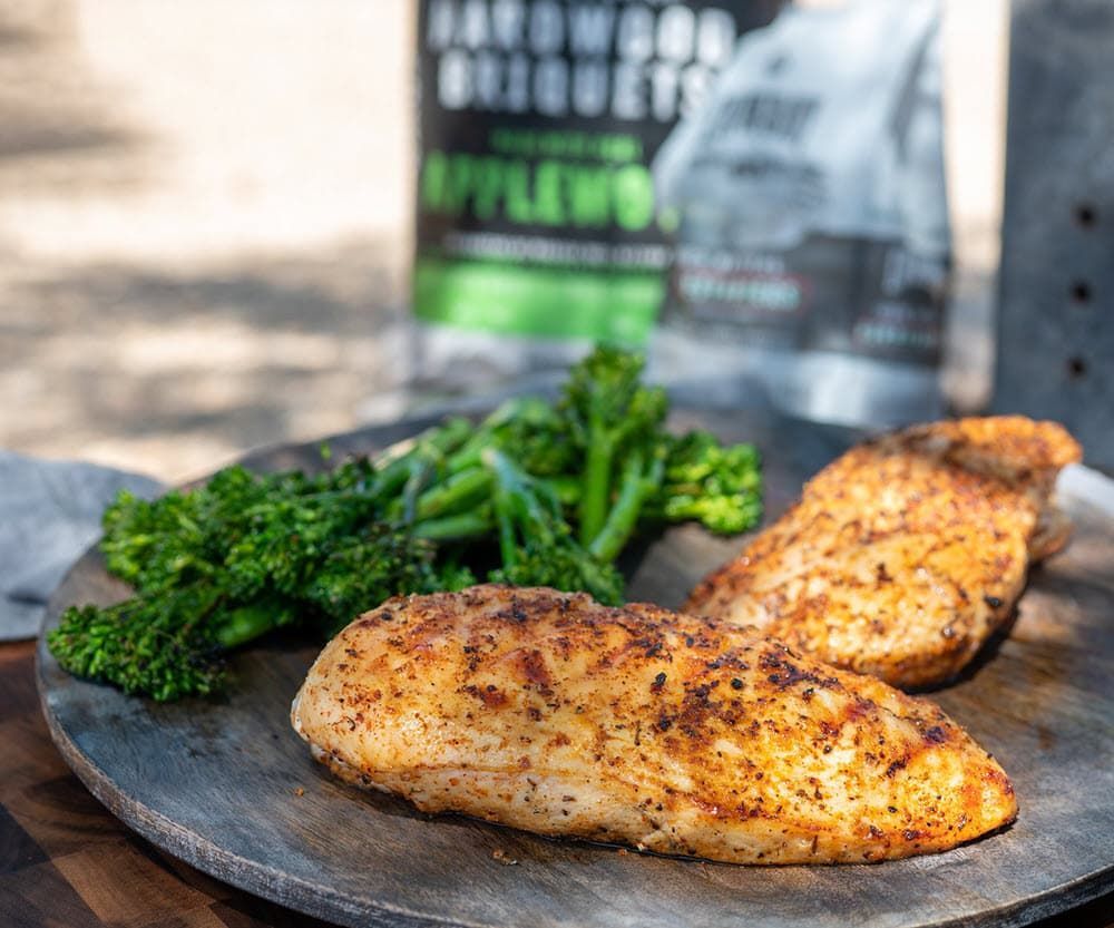 Grilled chicken breasts and broccolini on a wood plate