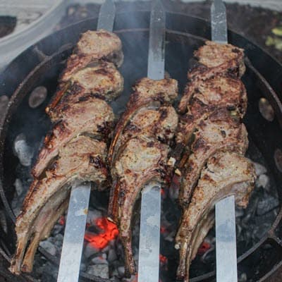 lamb chops on skewers cooking over live fire