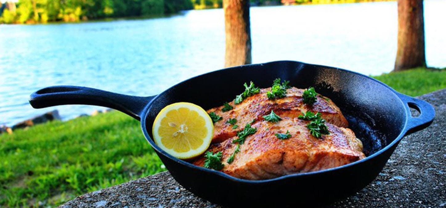 salmon in a cast iron pan garnished with lemon