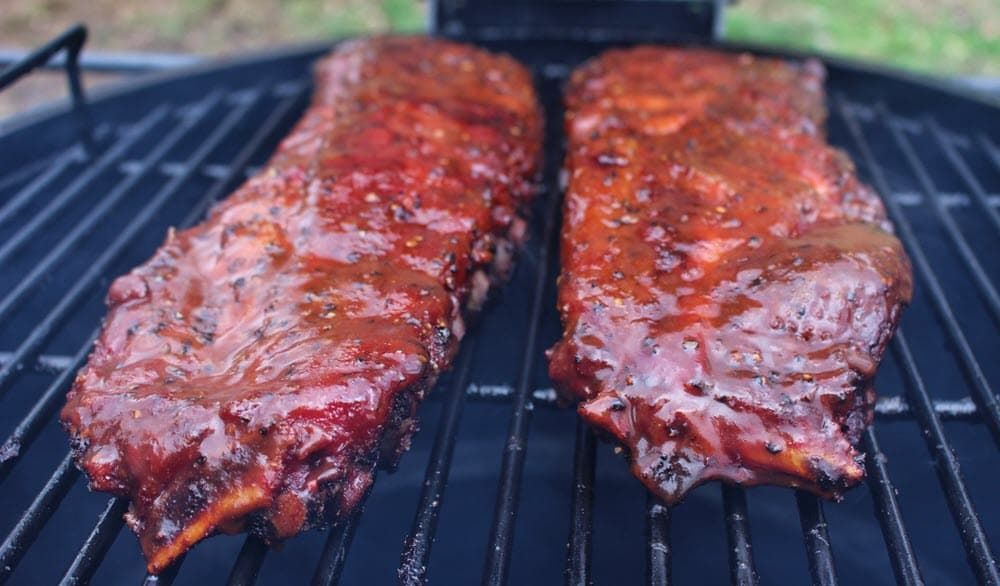 Glazed maple bourbon ribs cooking over live fire on the grill
