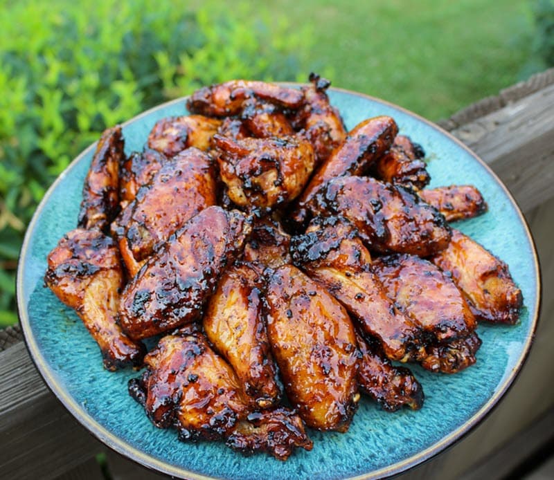 Grilled maple peach sticky wings piled on a plate