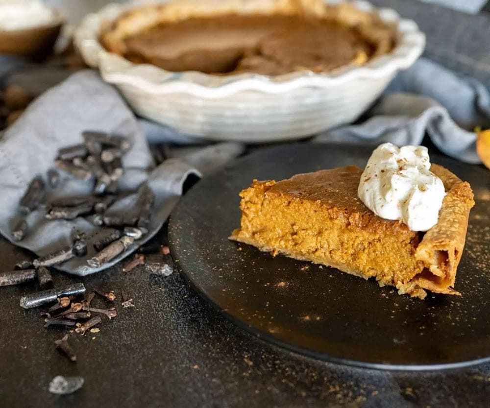 Slice of smoked pumpkin pie with whip cream on top