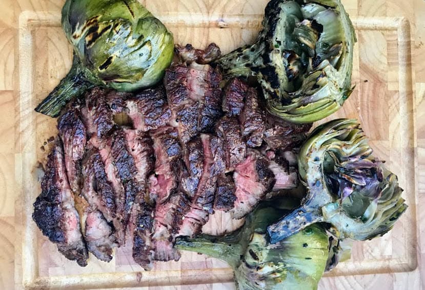 Ribeye Caps and Grilled Artichokes on a cutting board