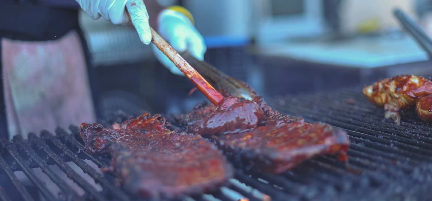 meat on the grill covered in bbq sauce