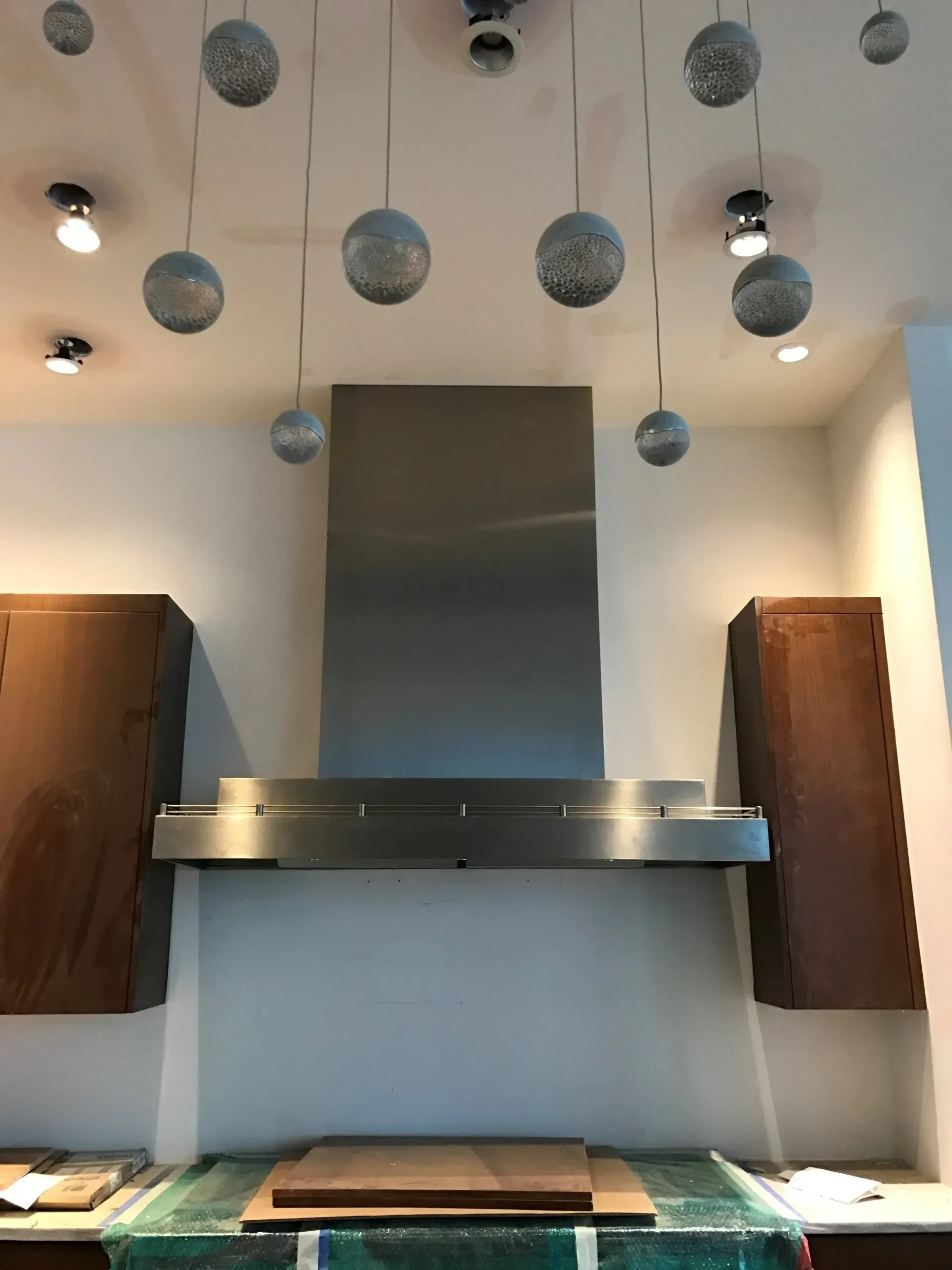 A kitchen with a stainless steel hood hanging from the ceiling