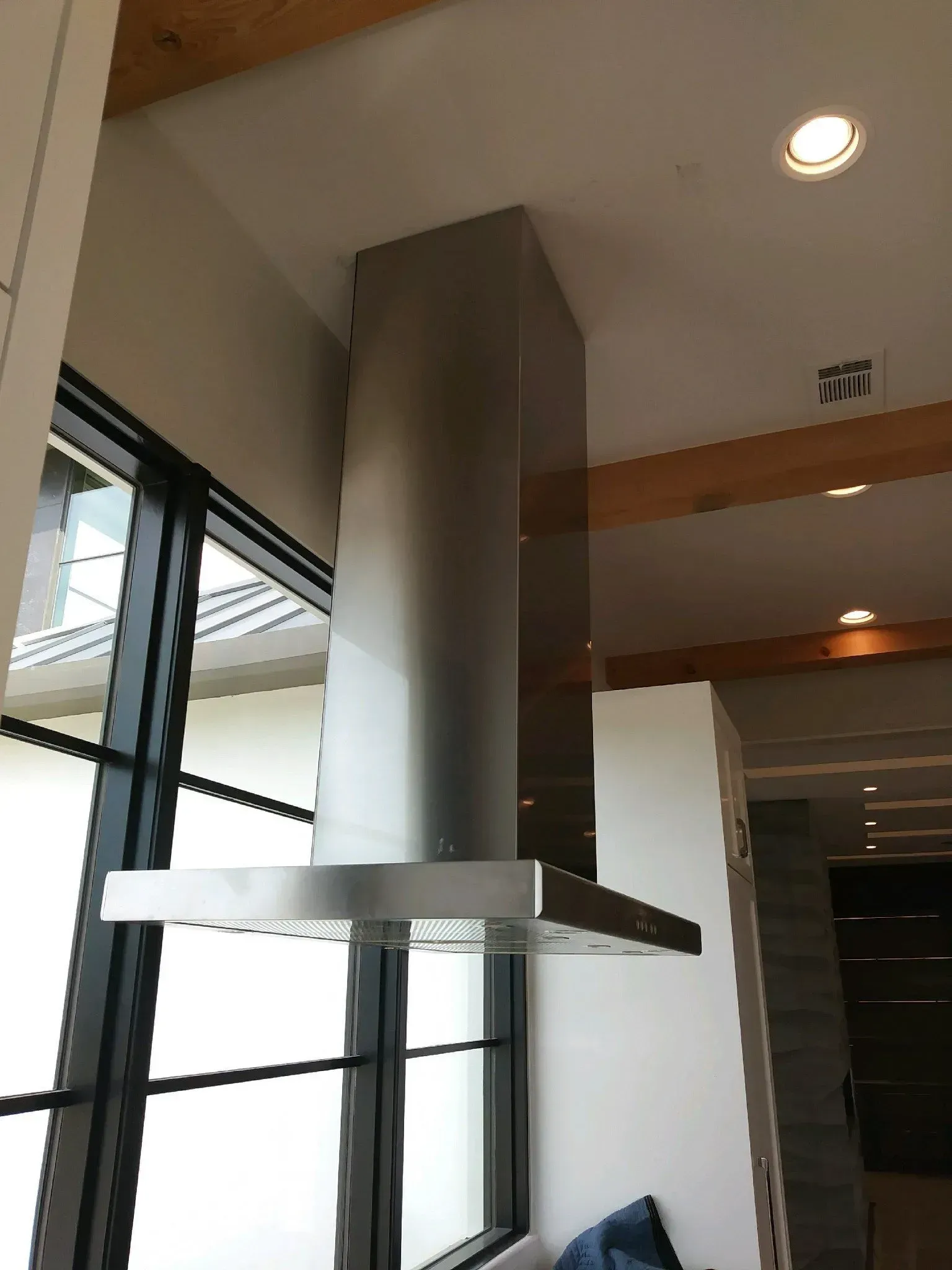 A stainless steel hood is hanging from the ceiling in a kitchen.