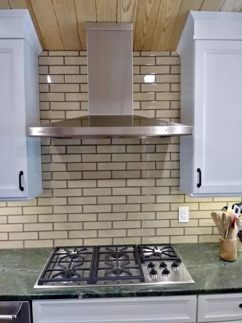 A kitchen with a stove top oven and a brick wall