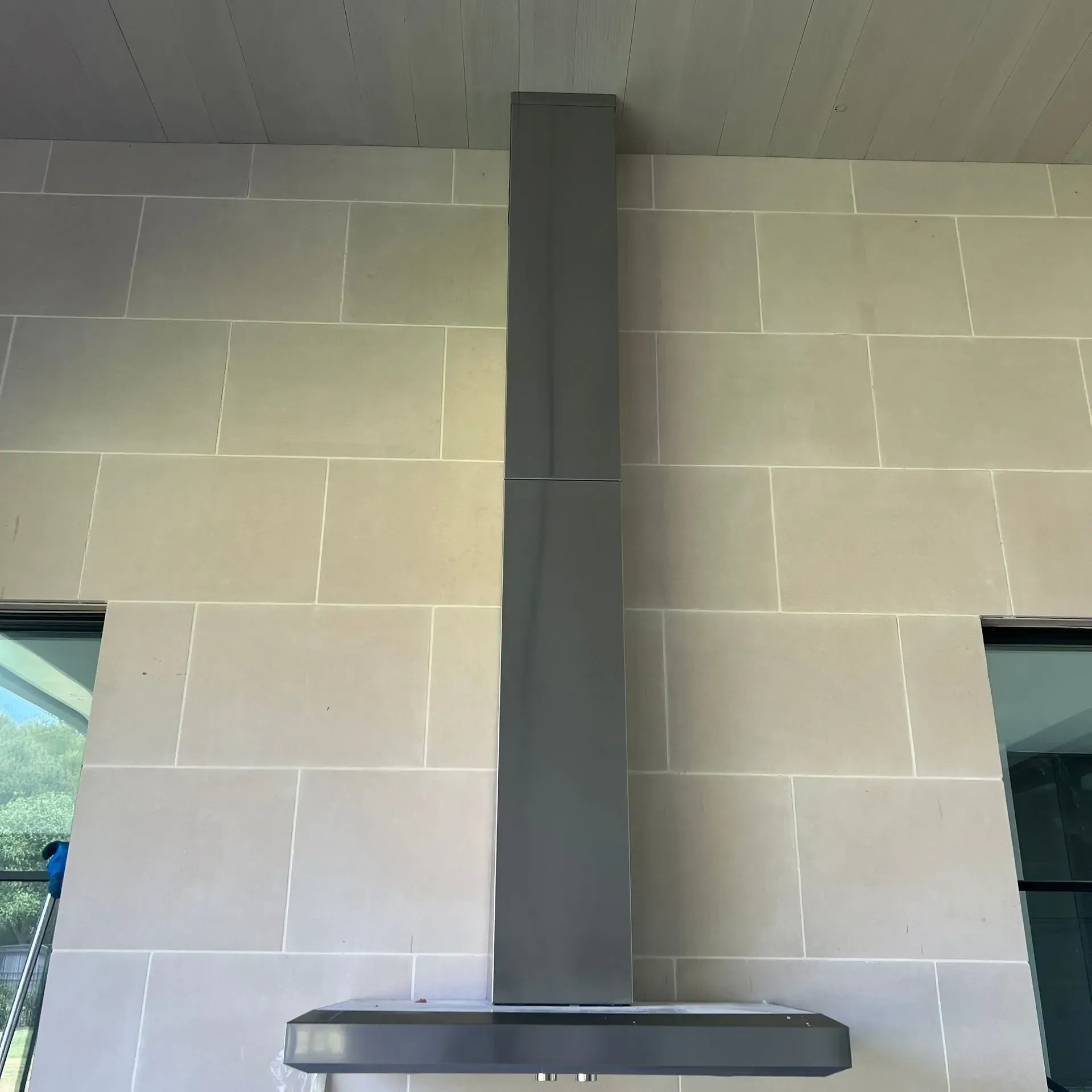 A stainless steel hood is mounted to a tiled wall