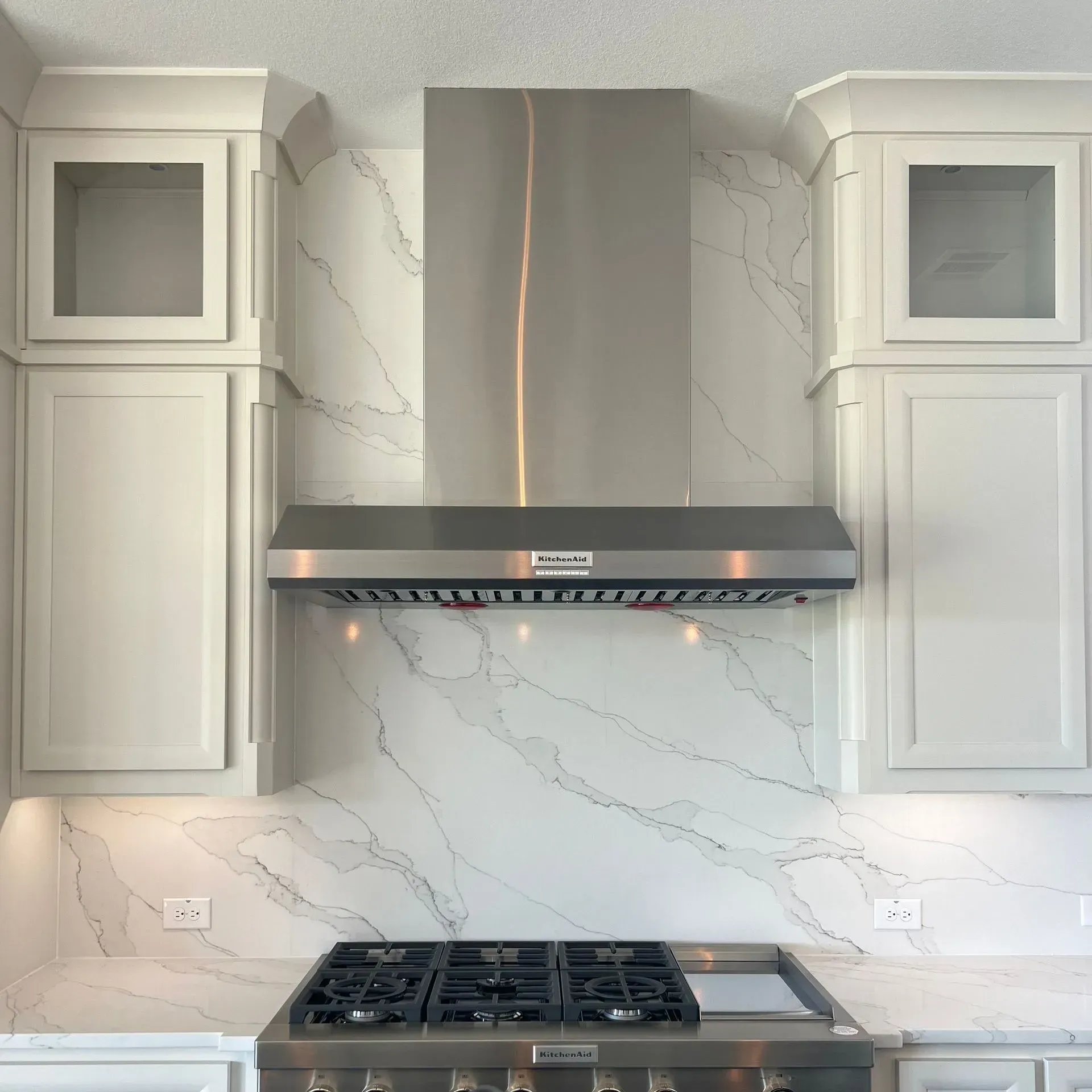 A kitchen with a stove top oven and a stainless steel hood