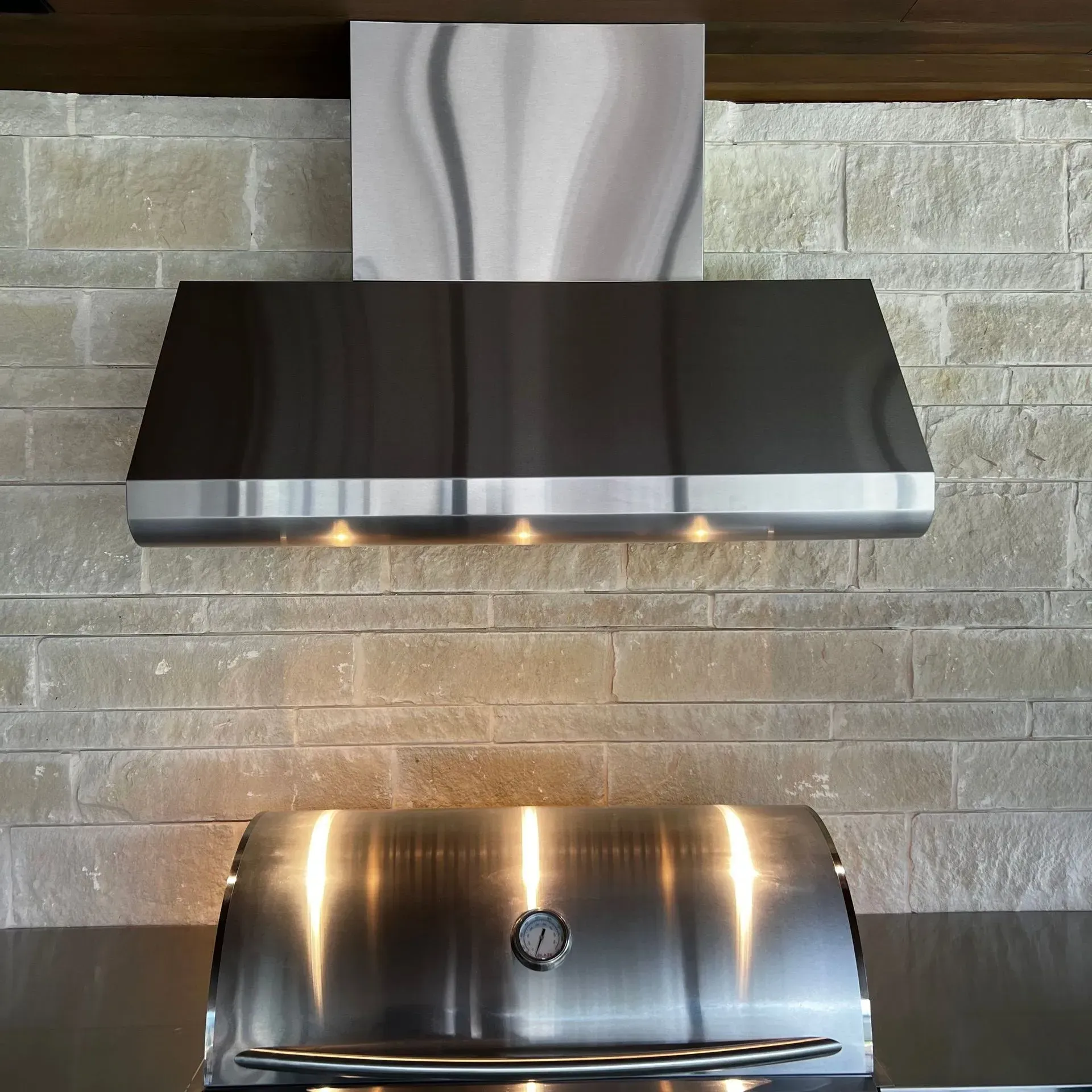 A stainless steel grill with a hood above it